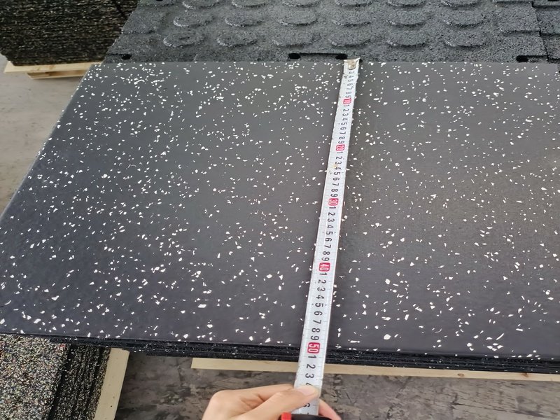 An engineer inspecting a roll of rubber gym flooring with calipers